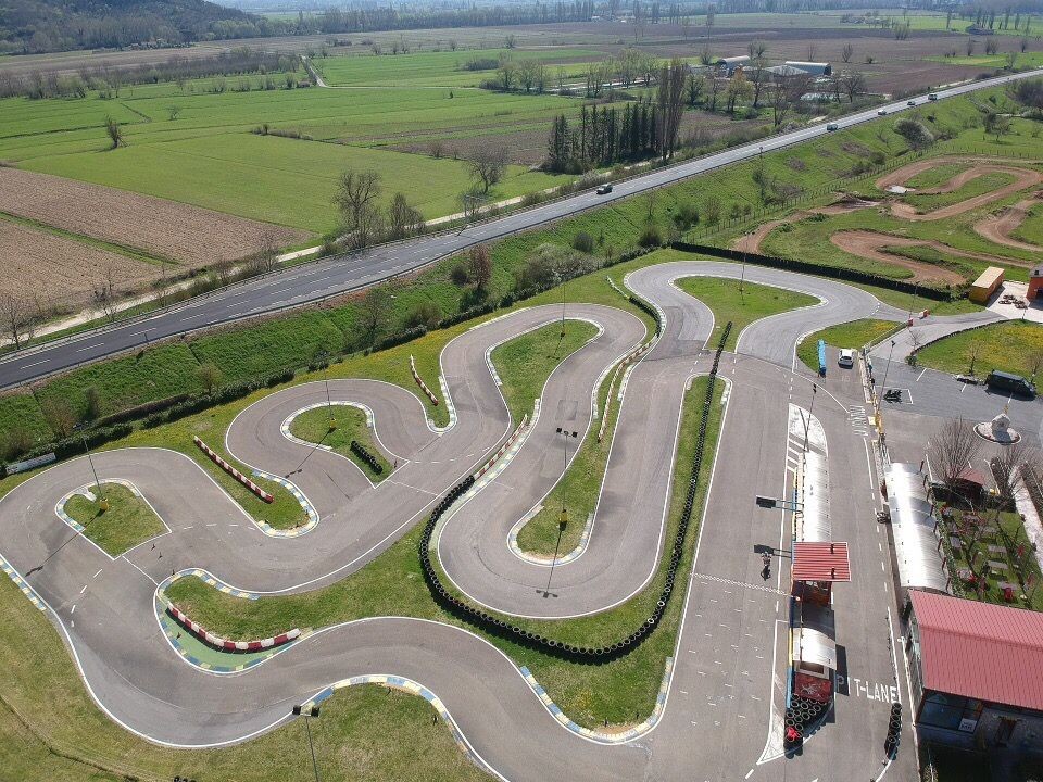 Aerial view of an outdoor go-kart track with winding paths and surrounding green fields.