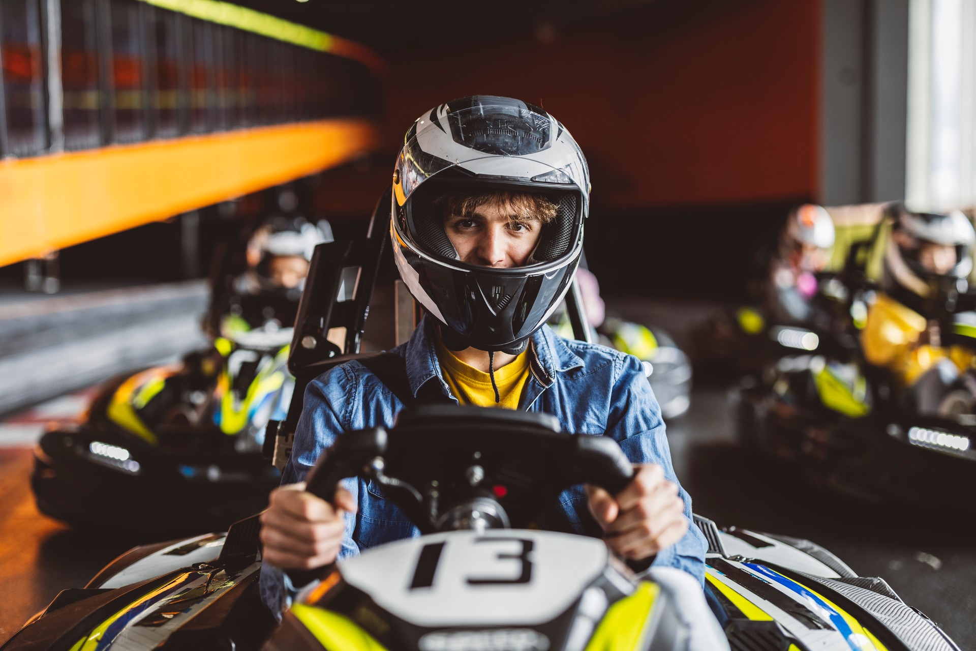 kart race close-up of concentrated boy in cart with helmet before starting race, rest of drivers in background