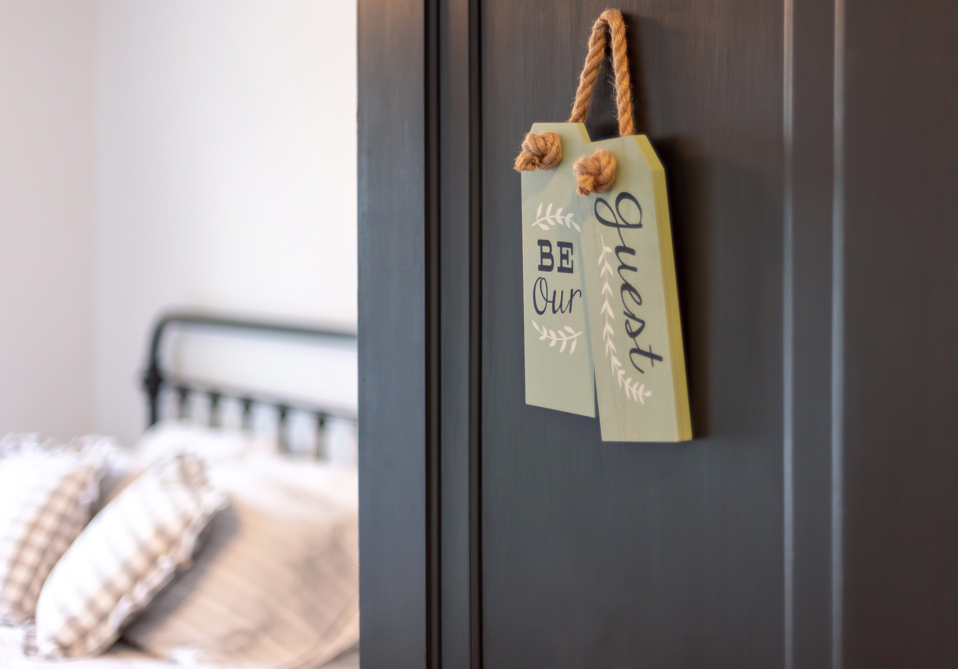 Open door to guest bedroom with a cute sign that says “Be our guest”